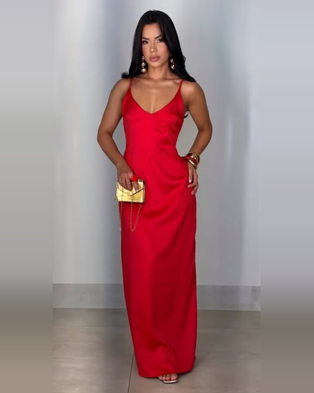 Vestido longo vermelho de cetim com alças finas e bolsa dourada, foto de corpo inteiro